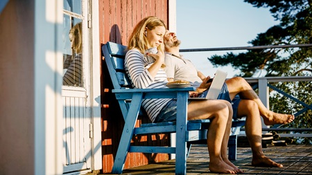 Kvinde og mand sidder på en bænk og nyder solen