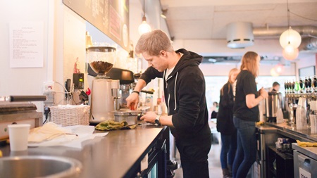 Young guy working at coffee shop Fra studie til job